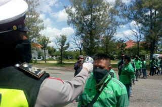 Ojok online dicek suhu tubuhnya oleh anggota Satlantas Polres Grobogan sebelum menerima paket sembako, Jumat (10/4/2020). (Semarangpos.com-Arif Fajar S.)