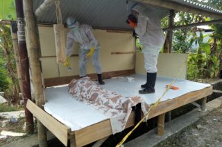 Petugas menggunakan alat pelindung diri lengkap memeriksa jenazah di pos kampling, Dusun Geneng, Desa Genengadal, Kecamatan Toroh, Kabupaten Grobogan, Jawa Tengah, Rabu (14/5/2020). (Semarangpos.com-Polsek Toroh)